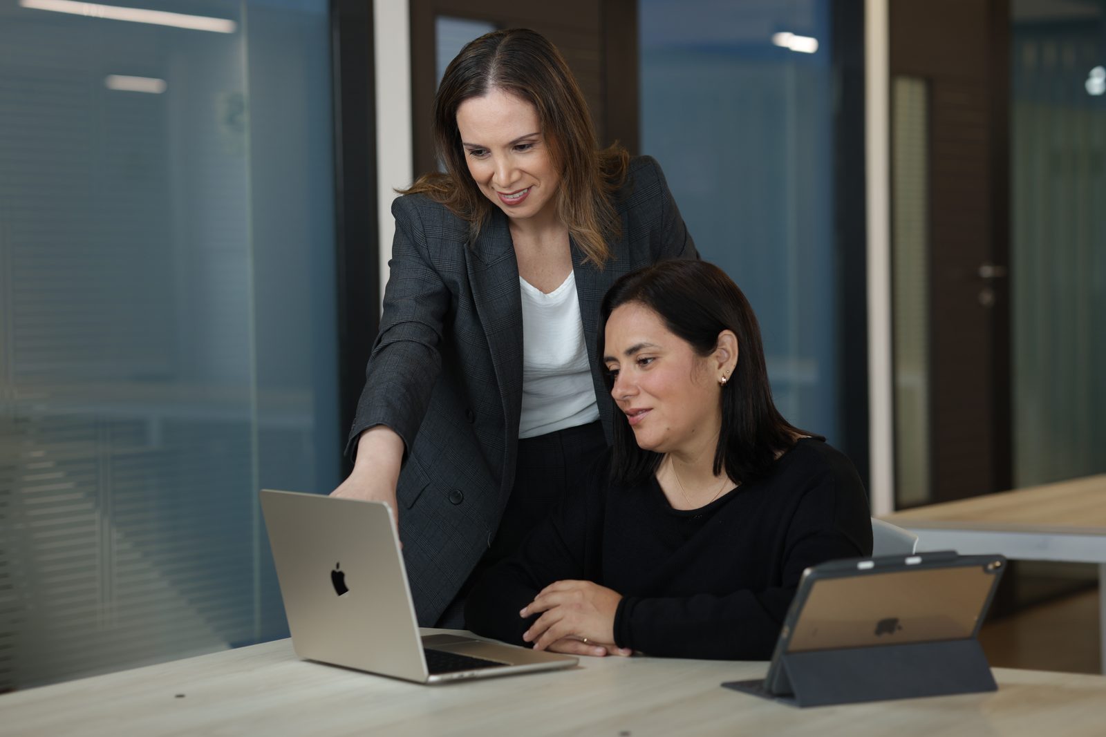 Johana Lúcar acompañando a una colega frente a la laptop en una sala de trabajo